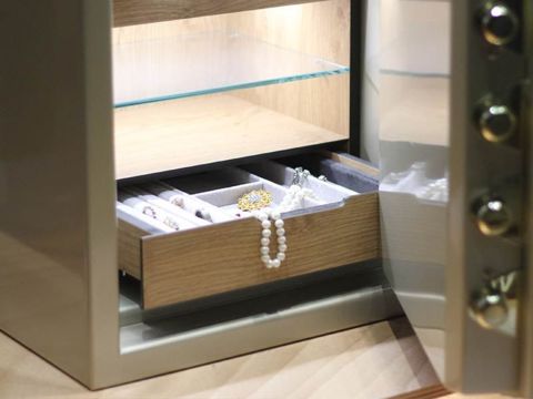 Goldener Hochglanztresor mit geöffneter Tür und Schmuck in einer Schublade